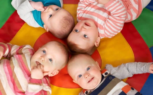 a group of babies lying on a colorful blanket