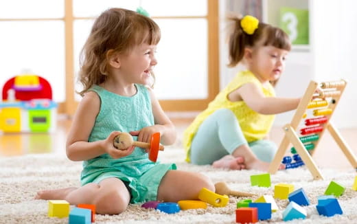 a couple of young girls playing with toys on the floor