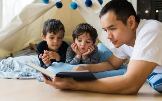 a person reading a book to a couple of children