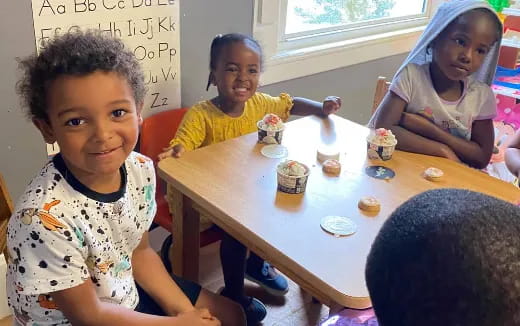 a group of children sitting around a table with food on it