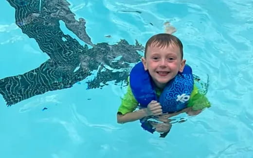 a boy in a pool with a dolphin