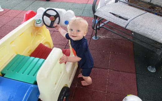 a baby standing next to a toy boat