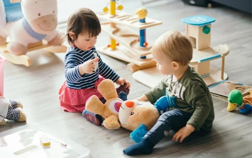 a couple of children playing with a stuffed animal