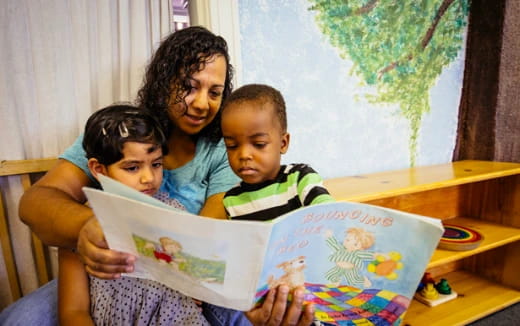 a person reading a book to a couple of children
