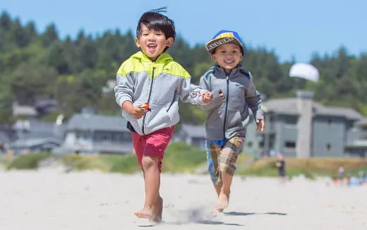 a couple of boys running on a beach