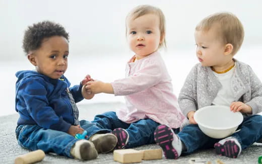 a group of children sitting on the floor eating from a bowl