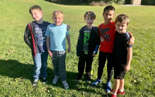 a group of boys standing in a grassy field