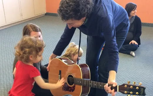 a man playing guitar with kids