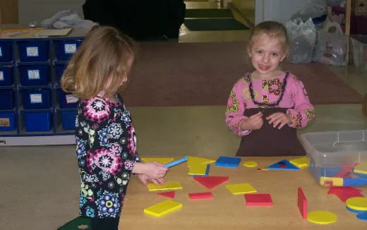 a couple of young girls playing with colorful blocks on the floor