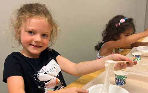 a couple of girls sitting at a table with food and drinks