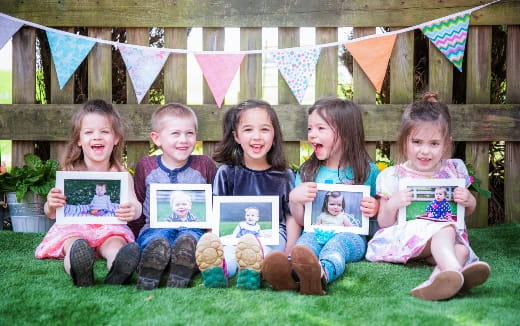 a group of children sitting on the grass holding books