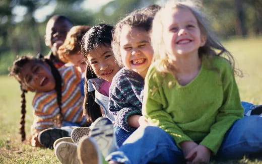 a group of children sitting in a circle smiling