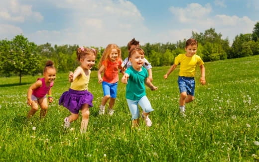 a group of children running in a grassy field