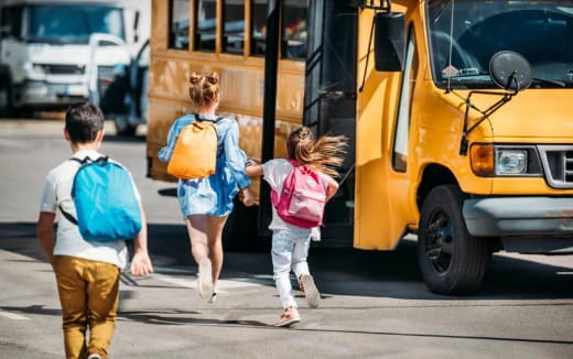 a group of people walking in front of a school bus