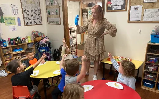 a person standing in front of a group of children sitting at a table