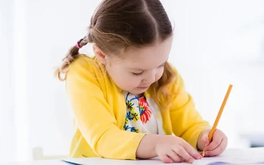a little girl writing on a piece of paper