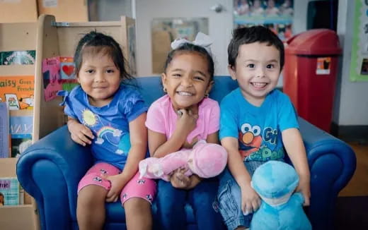 a group of children sitting on a blue chair