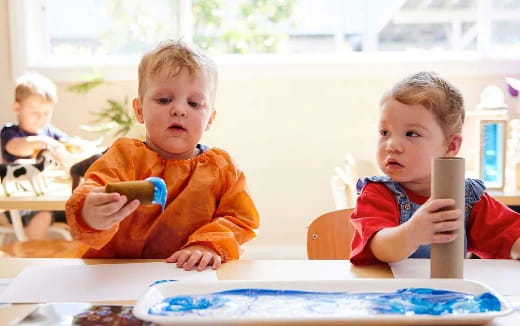 a couple of young boys sitting at a table with a blue plate