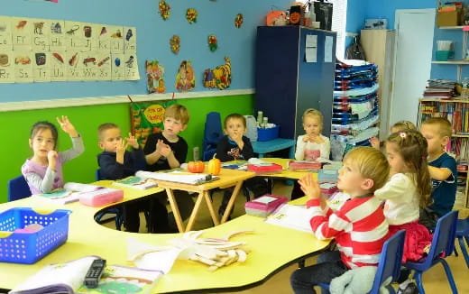 a group of children sitting at a table in a classroom