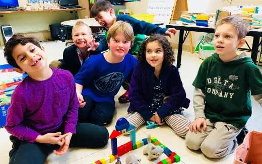 a group of children sitting on the floor with a toy