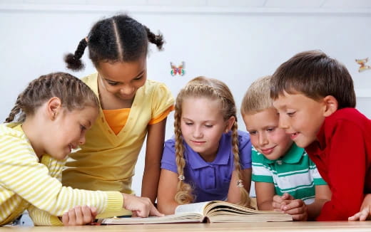 a group of children looking at a book