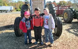 a group of children standing in front of a tractor