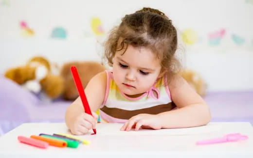a baby girl coloring on a paper