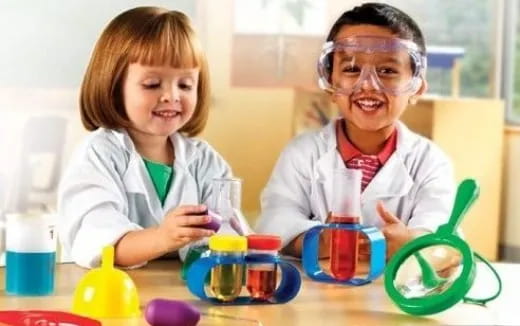 a person and a child wearing safety goggles and looking at a test tube