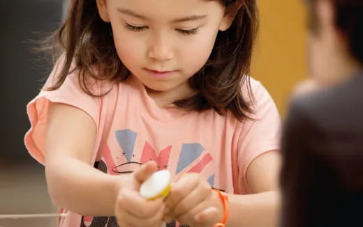 a girl holding a small pink bird