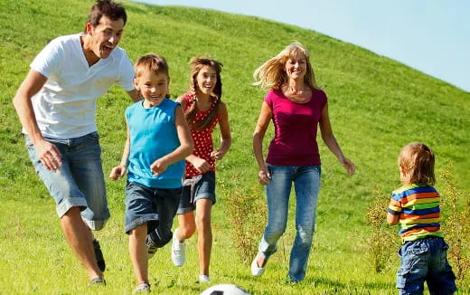 a family running on a grassy hill