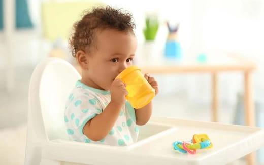 a baby drinking from a yellow cup