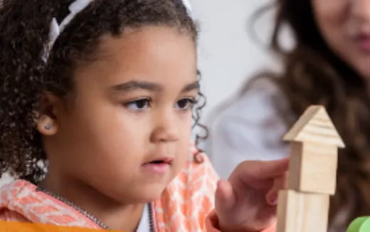 a young girl holding a wooden block