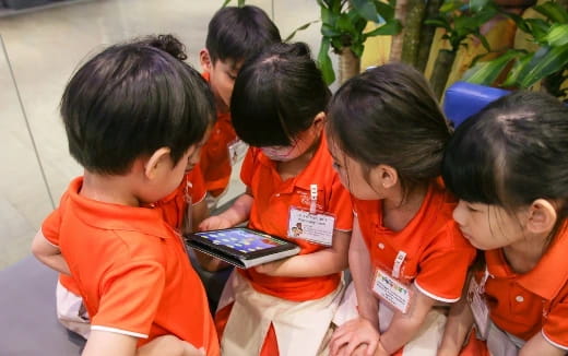 a group of children looking at a tablet