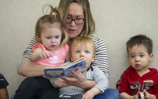 a person reading a book to a group of children