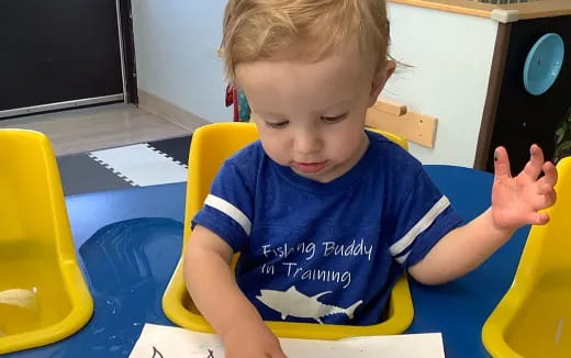 a child sitting in a highchair and holding a pen