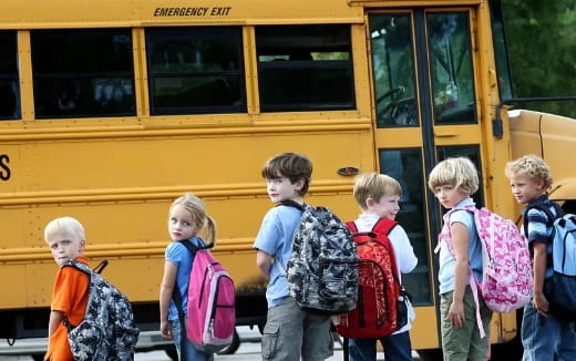 a group of children standing in front of a school bus