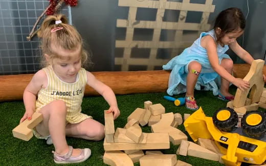 a couple of young girls playing with building blocks