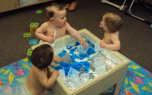 a group of babies playing with a cake