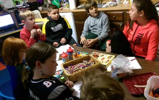 a group of children sitting around a table with food