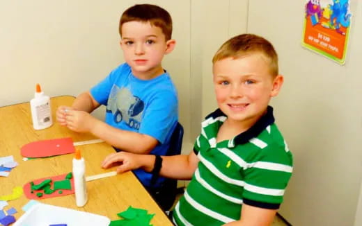 a couple of boys sitting at a table with toys