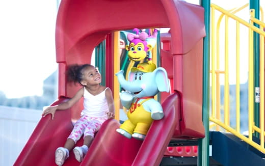 a girl sitting on a toy in a playground