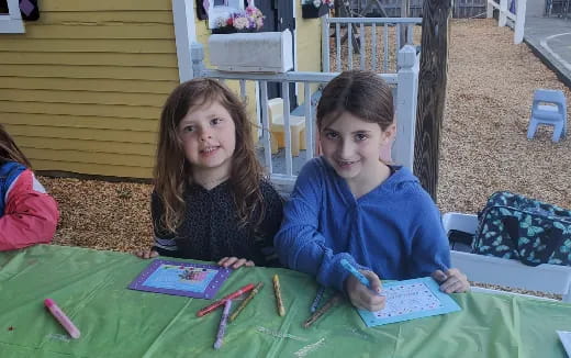 a boy and girl sitting at a table with a green tablecloth