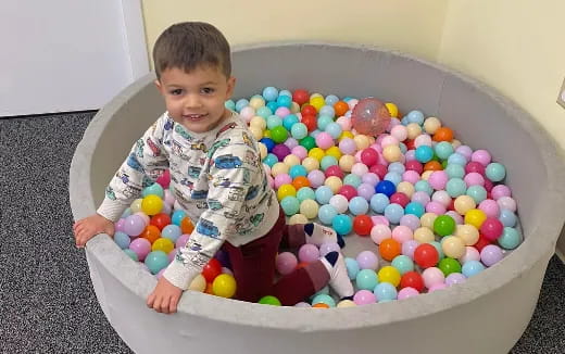 a boy sitting in a ball pit