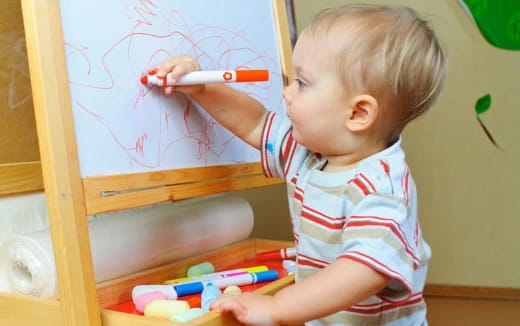 a baby drawing on a white board