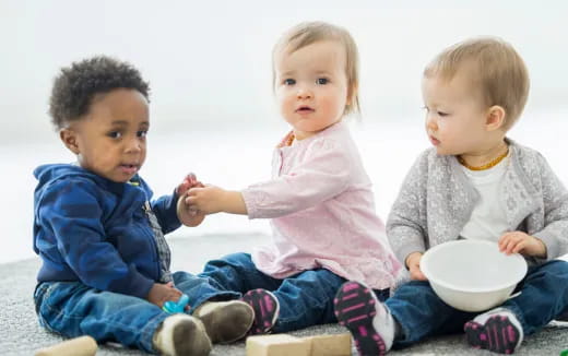 a group of children sitting on the floor eating from a bowl