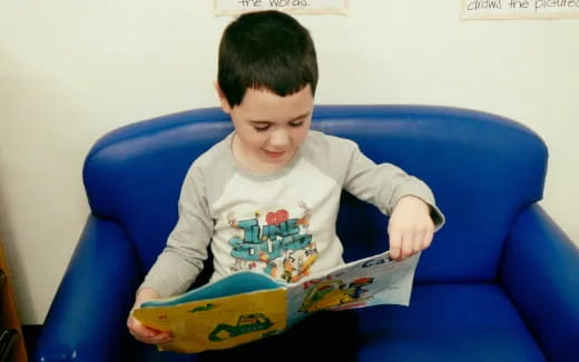 a child sitting on a blue couch reading a book