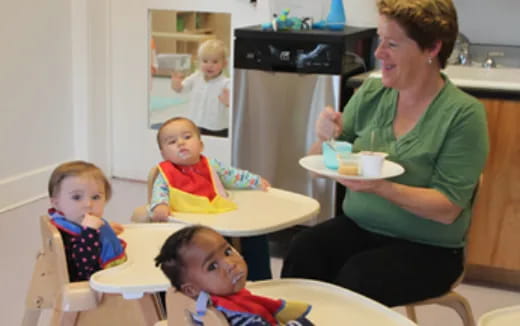 a person and a group of children sitting at a table