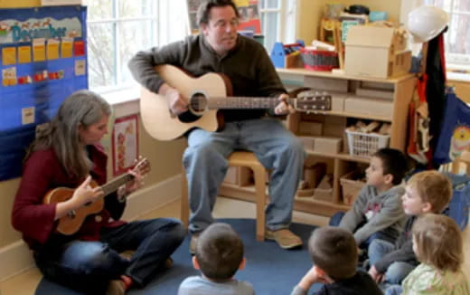 a person playing guitar to a group of children