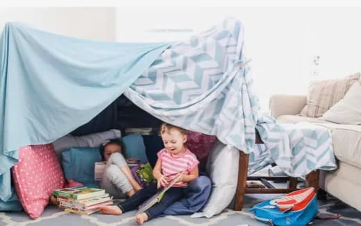 a couple of children sitting on a couch with a blue blanket over them