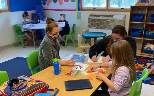 a group of children sitting at a table in a classroom